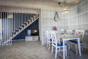 Um interior moderno com escada, sala de jantar e relógio fixado na parede.