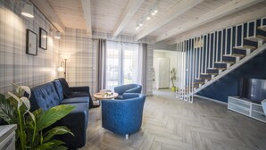 A modern living room with a sofa, armchair, and a small table. There is a staircase with a railing and a TV stand. - Two-story Holiday Home for 5 People, Summer Pool (Leba)