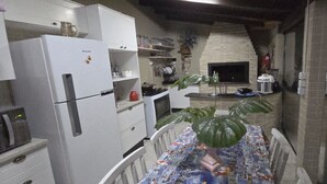 Une cuisine compacte équipée d’un four encastré, d’un réfrigérateur et d’une table à manger avec des chaises.