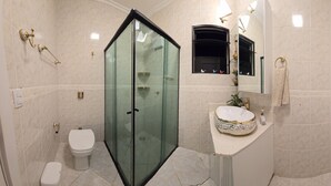 Une salle de bain moderne dotée d’une douche à parois de verre, de toilettes, d’un lavabo avec un receveur décoratif et d’un miroir avec un porte-serviettes.