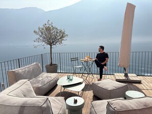 Ein Balkon mit Gartenmöbeln, einem Tisch mit Essen und Blick aufs Meer.