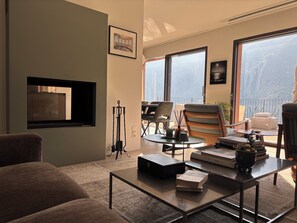 A living room with a sofa, coffee table, and chairs, a fireplace, and large windows with a view. - Unique lake house in gorgeous Gandria (Lugano)