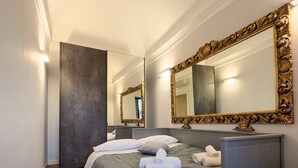 A hotel room with a large bed, a dresser, a mirror with an ornate frame, and a door leading to another room. - IL NIDO DEL DUOMO, cozy apartment in the historic center with a view of the cathedral (Catania)