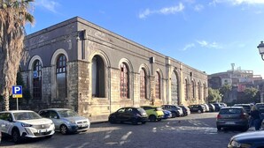 A building with arched windows and a parking lot with cars. - IL NIDO DEL DUOMO, cozy apartment in the historic center with a view of the cathedral (Catania)