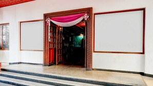 Een hotelentree met een rood plafond, een houten deur met een roze gordijn en een betegelde vloer.