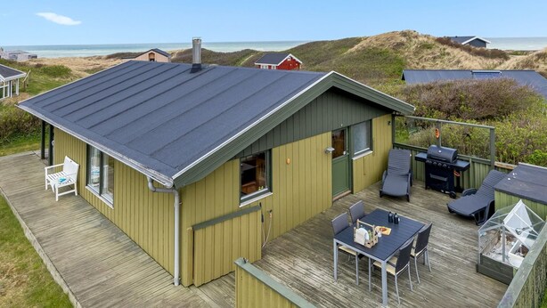 Ein Küstenhaus mit einer Terrasse, Sitzgelegenheiten im Freien und Blick aufs Meer.