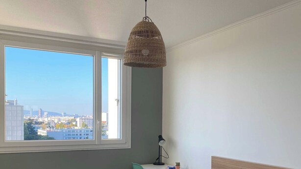 A bedroom with a bed, a desk, a chair, a hanging light fixture, and a window with a city view. - Cozy Room in a Friendly Shared Flat - Lyon 8th (Lyon)