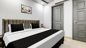 A bedroom with a bed, a gray door, and a painting on the wall. - Classic With Balconyshalimar Bagh (New Delhi)