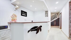 A reception area with a counter, a sign reading 'Collection,' and a staircase in the background. - Classic With Balconyshalimar Bagh (New Delhi)