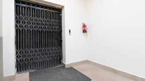 Ein verschlossenes Metalltor, ein an der Wand befestigter Feuerlöscher und ein Teppichboden.