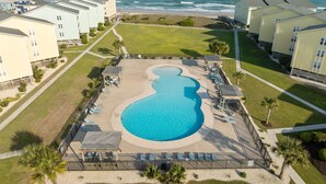 Een resort met een groot zwembad, uitzicht op het strand en meerdere gebouwen.