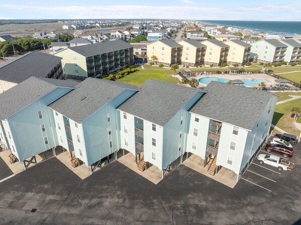 A multi-story hotel with a pool and a view of the ocean.