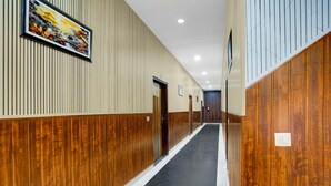 A hallway with wooden paneling, a black floor, and a painting on the wall. - Saver Double White Solitaire (Ludhiana)
