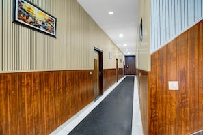 A hallway with wooden paneling, a black floor, and a painting on the wall. - Saver Double White Solitaire (Ludhiana)
