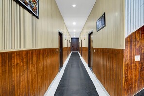 A long, narrow hallway with wooden paneling on the walls and a black carpet.