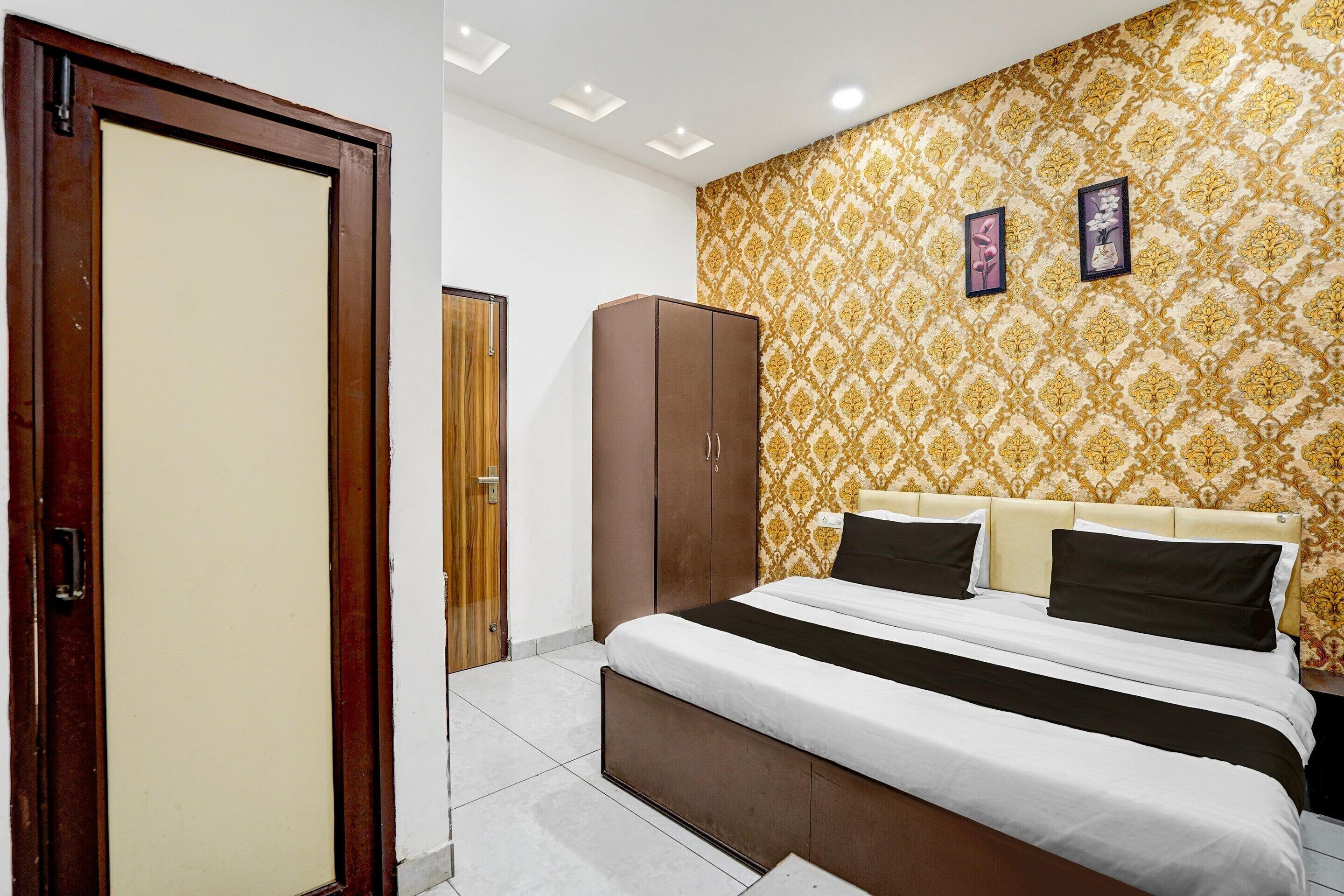 A bedroom with a bed, wardrobe, and patterned wallpaper.