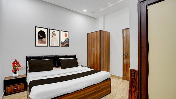 A modern bedroom with a bed, wooden wardrobe, and artwork on the wall. - Saver Double White Solitaire (Ludhiana)