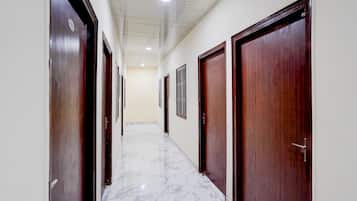 A hallway with wooden doors, white walls, and a marble floor.