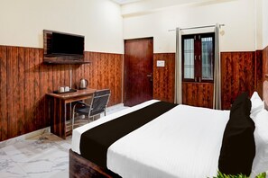 Une chambre d’hôtel comprenant un lit, un bureau avec une chaise, une télévision et une porte avec une fenêtre.