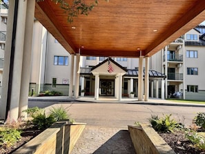 A hotel entrance with a covered walkway, American flag, and a sign indicating a danger warning.