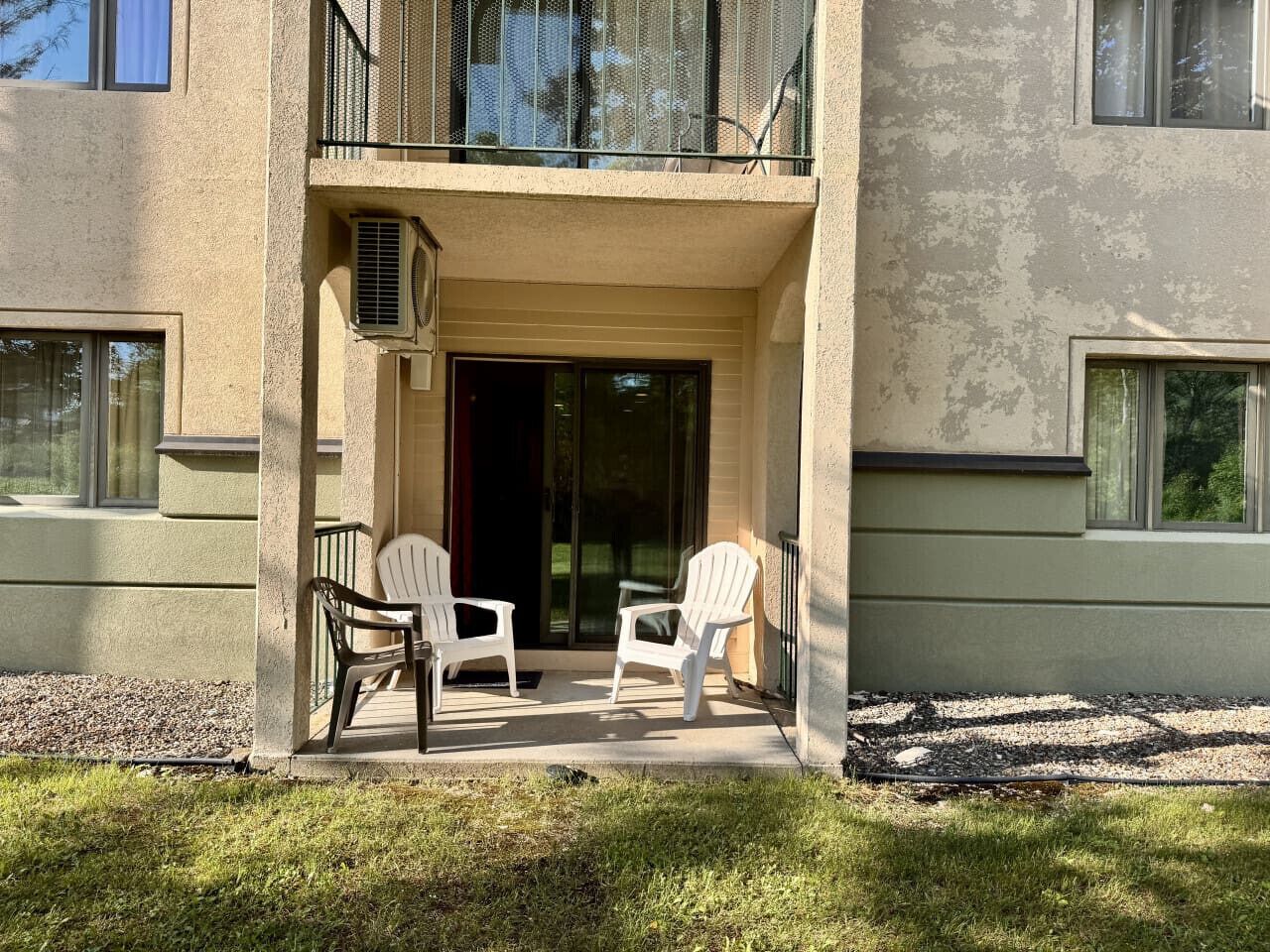 A building with a balcony, two white chairs, and a small table.