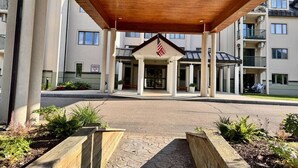Ein Hotel Eingang mit überdachter Zugang, amerikanischer Flagge und einem Schild, das vor einer Gefahr warnt.