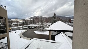 Schneebedeckte Landschaft mit einer gewundenen Straße, Gebäuden und einem Berg im Hintergrund.