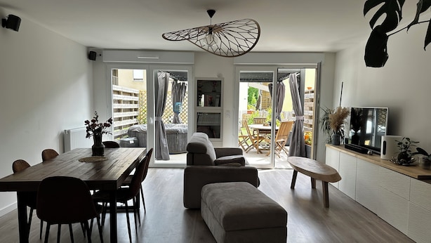 A modern living room with a dining table, sofa, and TV. - A Family Spa Getaway Amid Meadows, Birds, and Gardens (Chantepie)