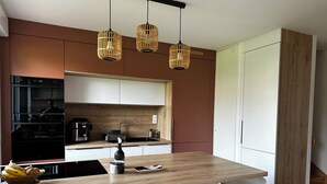 A modern kitchen with a central island, stainless steel appliances, and a wooden countertop. - A Family Spa Getaway Amid Meadows, Birds, and Gardens (Chantepie)