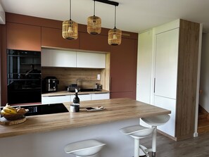 Une cuisine moderne dotée d’un îlot central, d’appareils électroménagers en acier inoxydable et d’un plan de travail en bois.