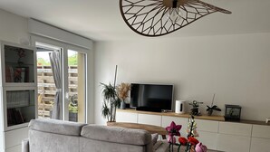 A modern living room with a sofa, a dining table, a TV, and a bookshelf. - A Family Spa Getaway Amid Meadows, Birds, and Gardens (Chantepie)