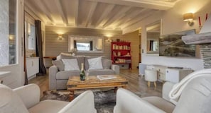 A cozy living room with a sofa, coffee table, and a fireplace. - Charming apartment in the heart of Megève with terrace and mountain view (Combloux)