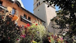 Un edificio con un campanario, rodeado de exuberante vegetación y plantas en flor.