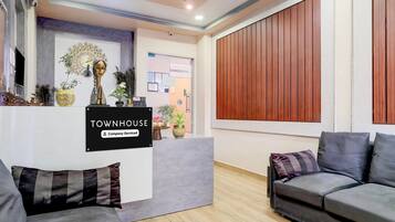 A reception area with a sign reading 'TOWNHOUSE Company-Serviced,' a reception desk, a peacock wall decoration, and a wooden panel wall.