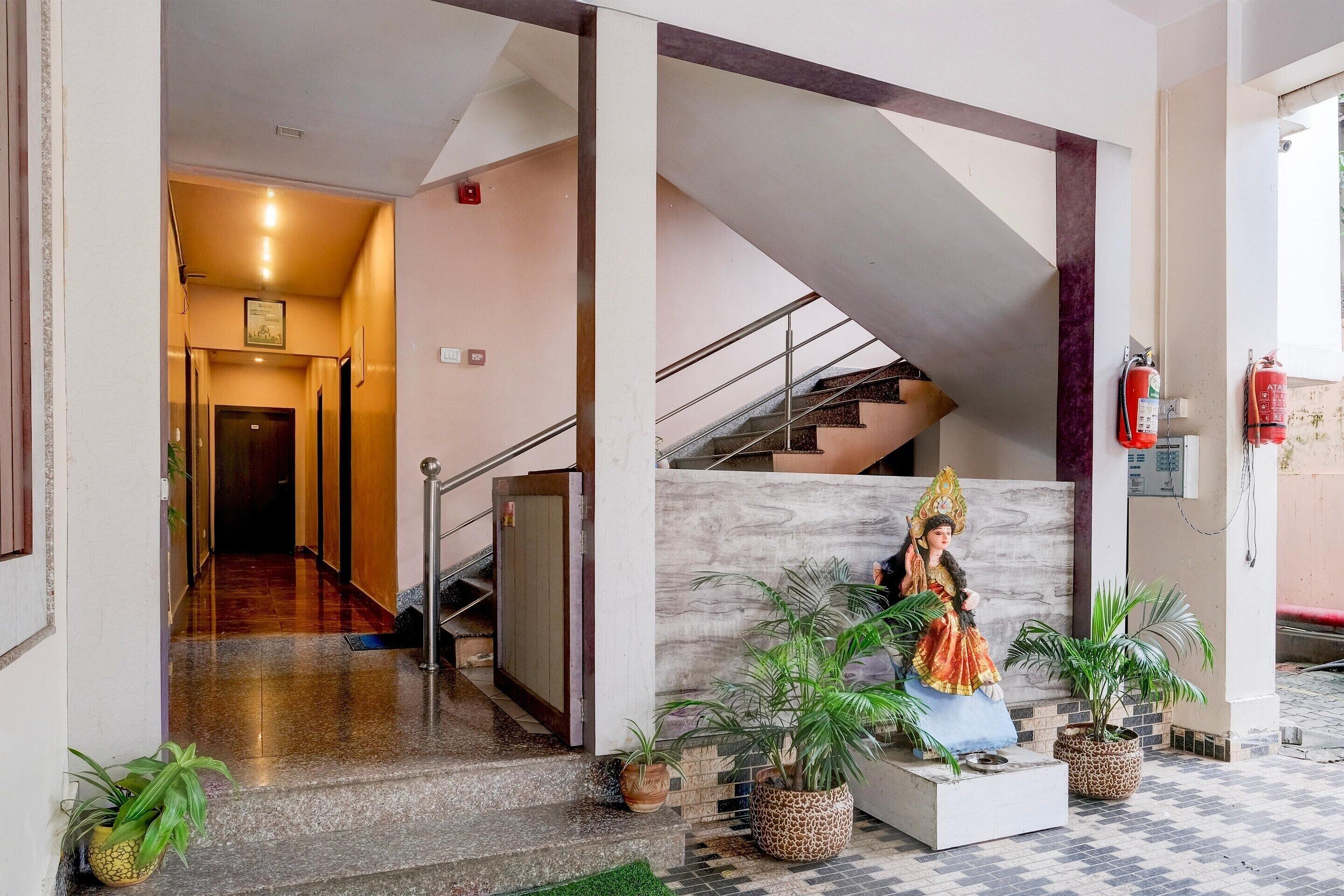 A hotel lobby with a statue, a staircase, and potted plants.