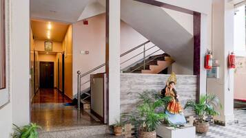 A hotel lobby with a statue, a staircase, and potted plants.
