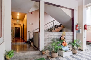 A hotel lobby with a statue, a staircase, and potted plants. - Classic With Balcony Beltola Tiniali Pratishtha (Guwahati)