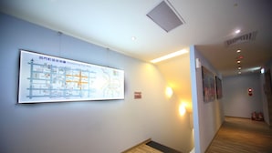 A hallway with a map, wall-mounted lights, and fire extinguishers. - Ehouse Hotel Xining Banch (Taipei)