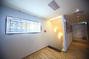 A hallway with a map, wall-mounted lights, and fire extinguishers. - Ehouse Hotel Xining Banch (Taipei)