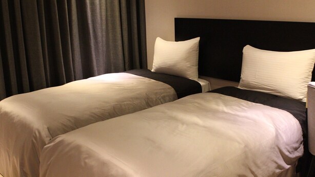 A hotel room with two beds, dark curtains, and a plain wall. - Ehouse Hotel Xining Banch (Taipei)