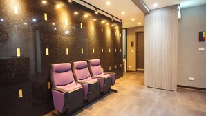 A hotel lobby with a seating area featuring purple chairs, a black marble wall with gold accents, and a wooden door. - Ehouse Hotel Xining Banch (Taipei)