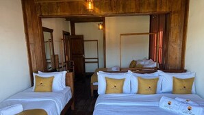 Ein Hotelzimmer mit zwei Einzelbetten, einer Holzbalkendecke und einem Spiegel.