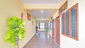 A hallway with potted plants, wooden doors, and a tiled floor. - Saver Double Sunshine Guest House (Dehradun)