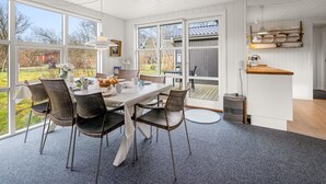 A dining area with a table set for four, surrounded by wicker chairs, large windows, and a view of the outdoors. - "Ascan" - 300m to the fjord by Interhome (Tarm)