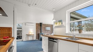 A modern kitchen with a wooden countertop, white cabinetry, a brick accent wall, and a large window. - "Ascan" - 300m to the fjord by Interhome (Tarm)
