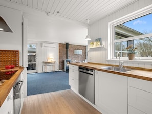 Eine moderne Küche mit Holz Arbeitsplatte, weißen Schränken, einer Ziegelwand und einem großen Fenster.