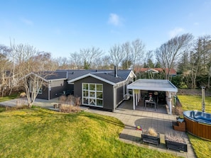 Ein modernes Haus mit Terrasse, Whirlpool und überdachter Außenbereich zum Sitzen.