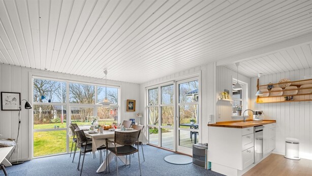 A modern kitchen with white cabinetry, a wooden countertop, and a dining area with a table and chairs. - "Ascan" - 300m to the fjord by Interhome (Tarm)