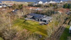 A modern house with a large deck, surrounded by trees and a view of the sea. - "Ascan" - 300m to the fjord by Interhome (Tarm)