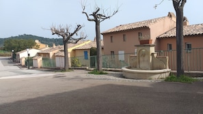 A residential street with houses, a fountain, and a clear sky. - Le Mazet du bonheur Issambres (Roquebrune-sur-Argens)